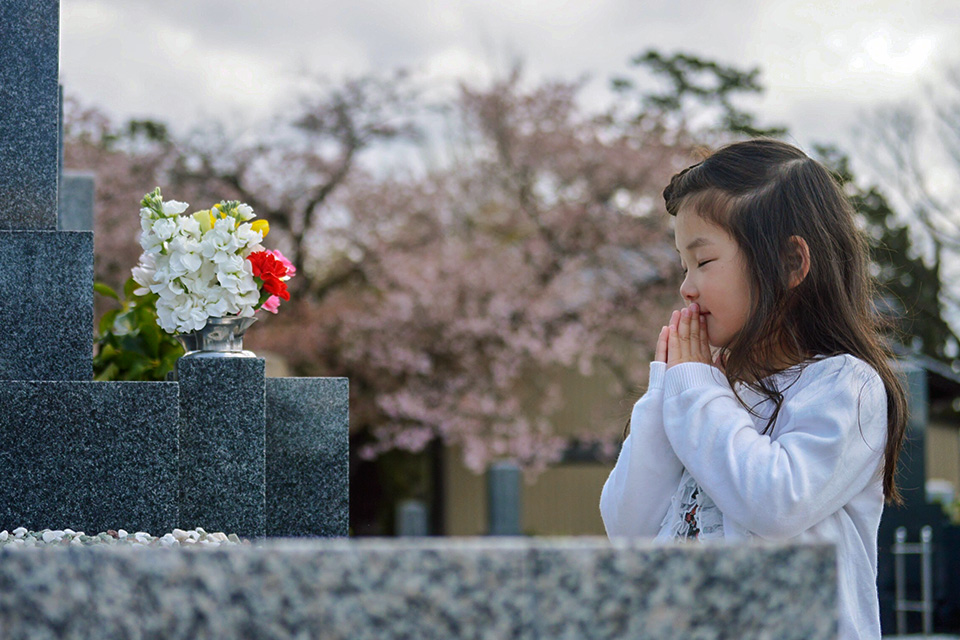 お墓でお参りしている女の子